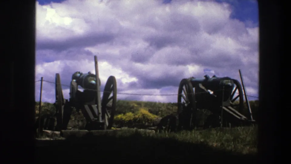 1975 Copenhagen 8mm view of two displayed cannons on grassy battlements, bordered by a dark arch or wall.