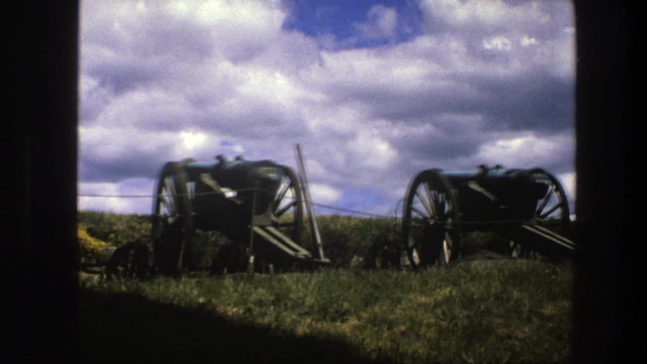 1975 Copenhagen 8mm frame with two historic cannon carriages on grass, seen through a dark doorway or window-like edge.