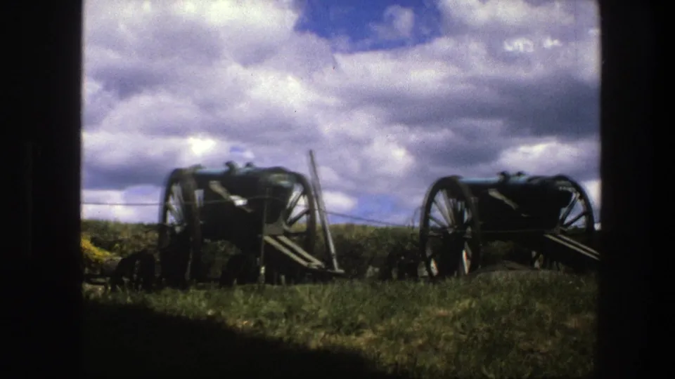 1975 Copenhagen 8mm frame with two historic cannon carriages on grass, seen through a dark doorway or window-like edge.