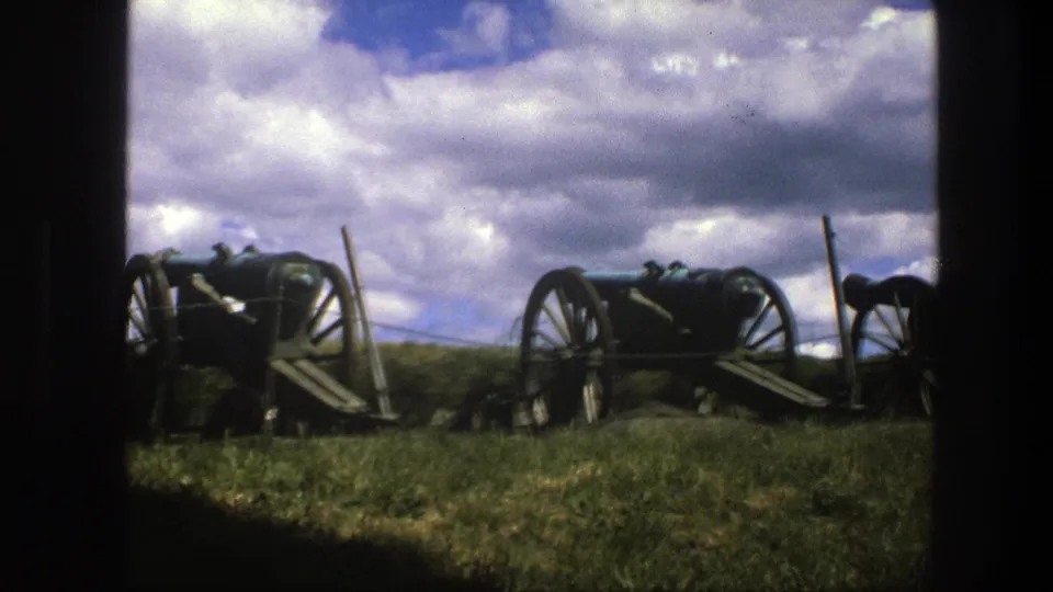 1975 Copenhagen 8mm frame showing a wider row of historic cannons on wheeled carriages in an outdoor grassy display.