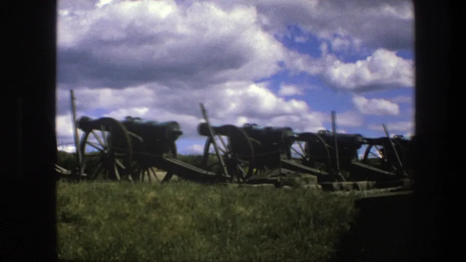 1975 Copenhagen 8mm still of antique war cannons on wooden carriages viewed from a shaded or bordered vantage point.