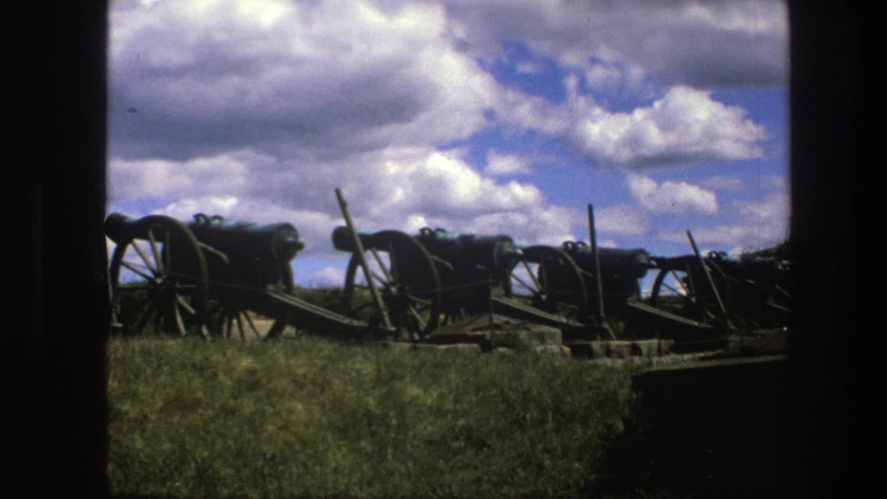 1975 Copenhagen 8mm frame showing historic cannons lined across a grassy field, partly bordered by a dark foreground frame.