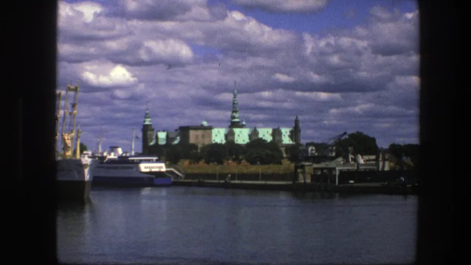 1975 Copenhagen harbor view with white boats on the water and Amalienborg Palace architecture under puffy clouds.
