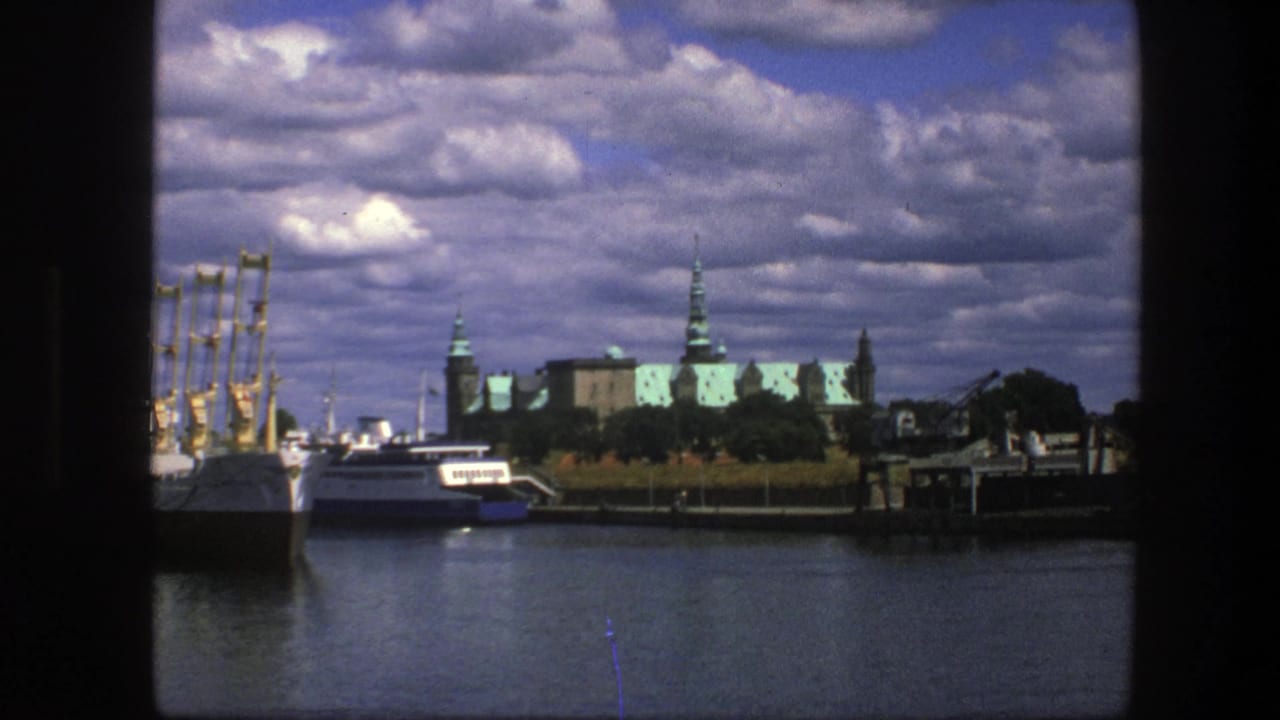 Copenhagen waterfront in 1975, showing white boats near the harbor and palace buildings below a dramatic cloudy sky.