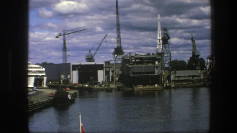 Copenhagen harbor in 1975 with cranes, dock buildings, dark water and part of a ship visible at the right edge.