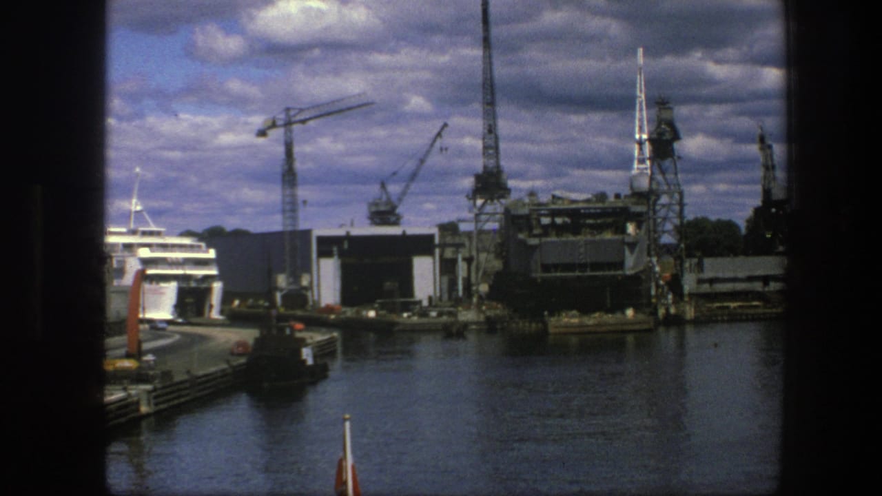 Copenhagen harbor with a docked passenger ship, cranes, water, and cloudy sky.