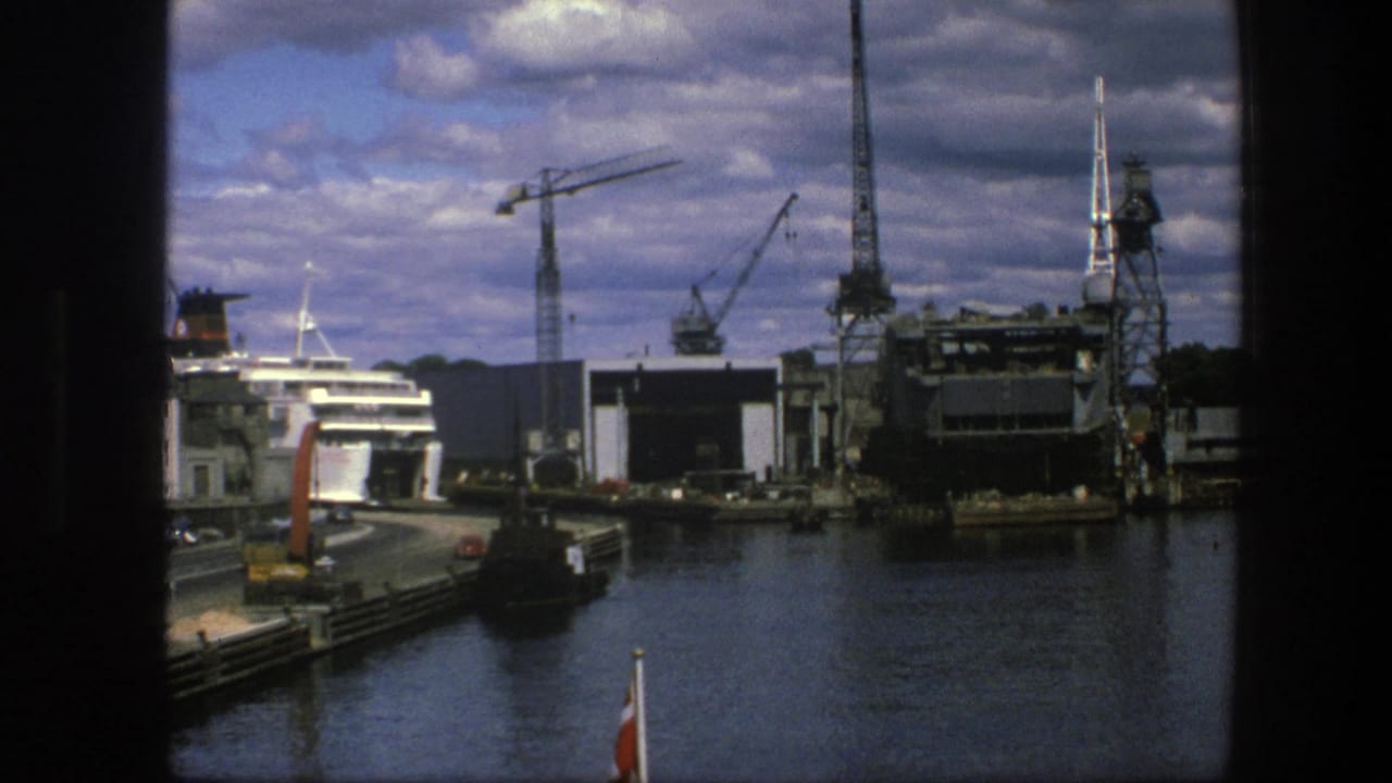 Harbor water, cranes, dock structures, and a passenger ship near the left edge.