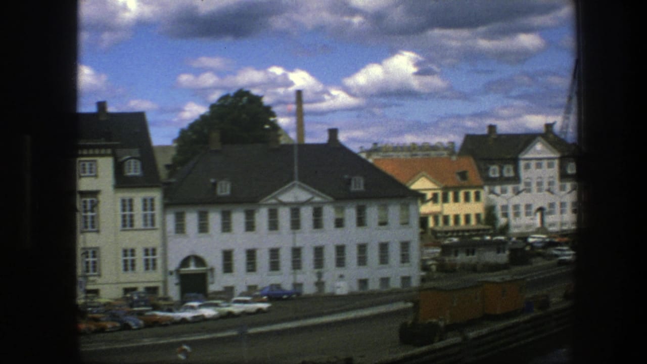 White and tan buildings beside a street under blue sky and clouds.
