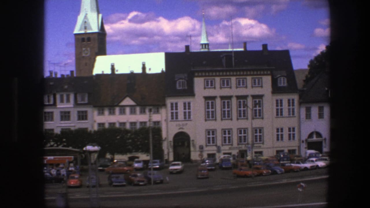 Waterfront buildings with spires, parked cars, and dark film-frame borders.