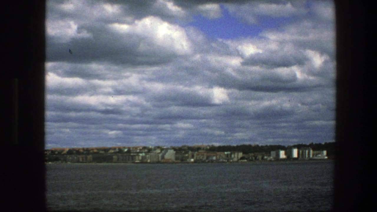 Wide water view with a distant city shoreline and layered clouds.