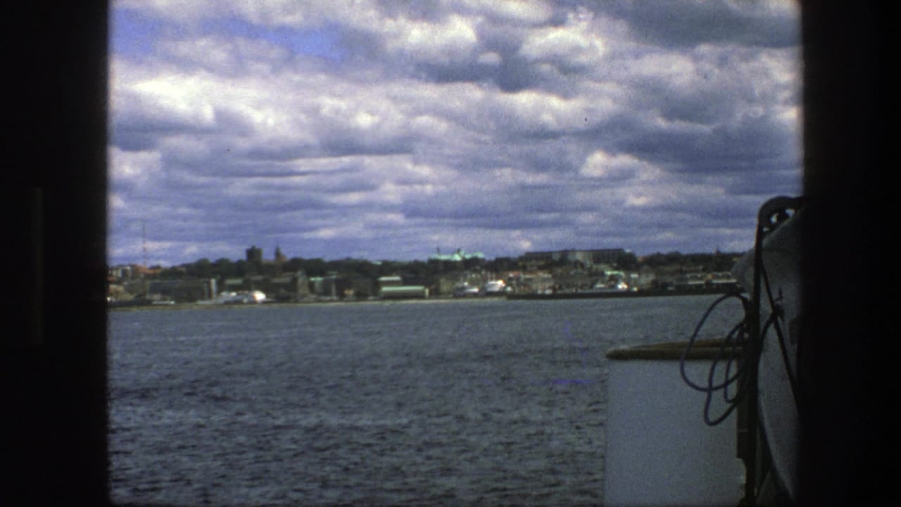Copenhagen waterfront seen across water from a boat under heavy clouds.