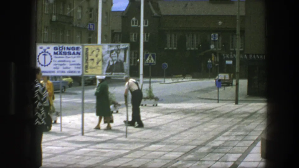 1975 Copenhagen street scene with pedestrians on a paved plaza near advertising signs, storefronts, and Skandinaviska Banken signage.