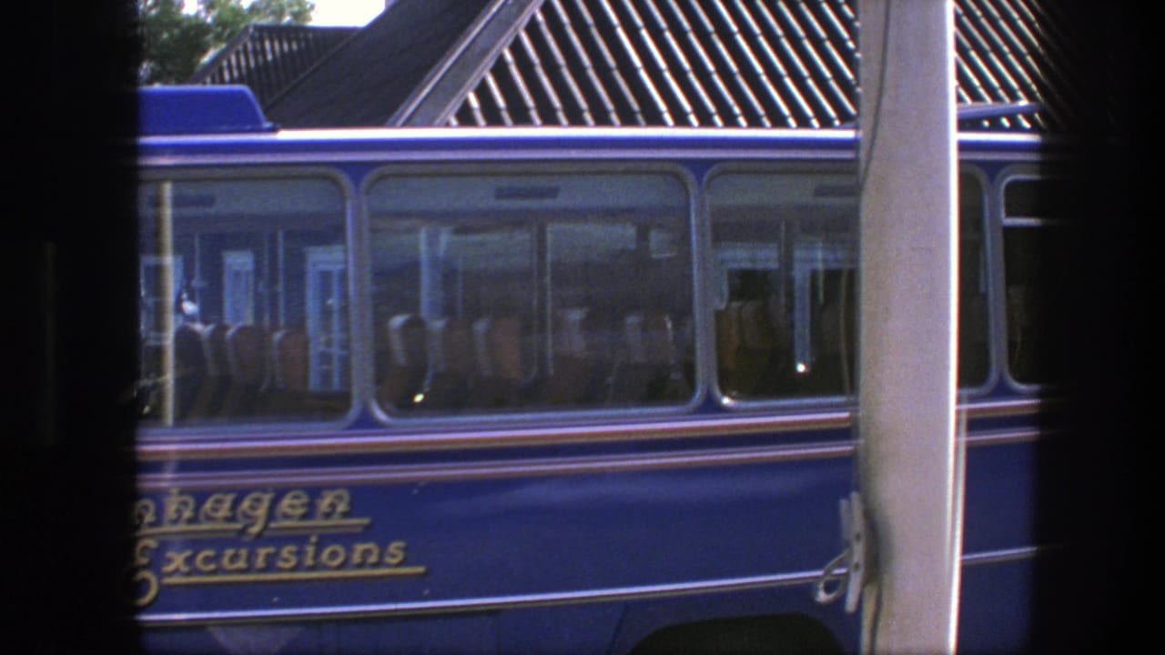 Blue tour bus with Copenhagen Excursions lettering seen through dark vertical edges.