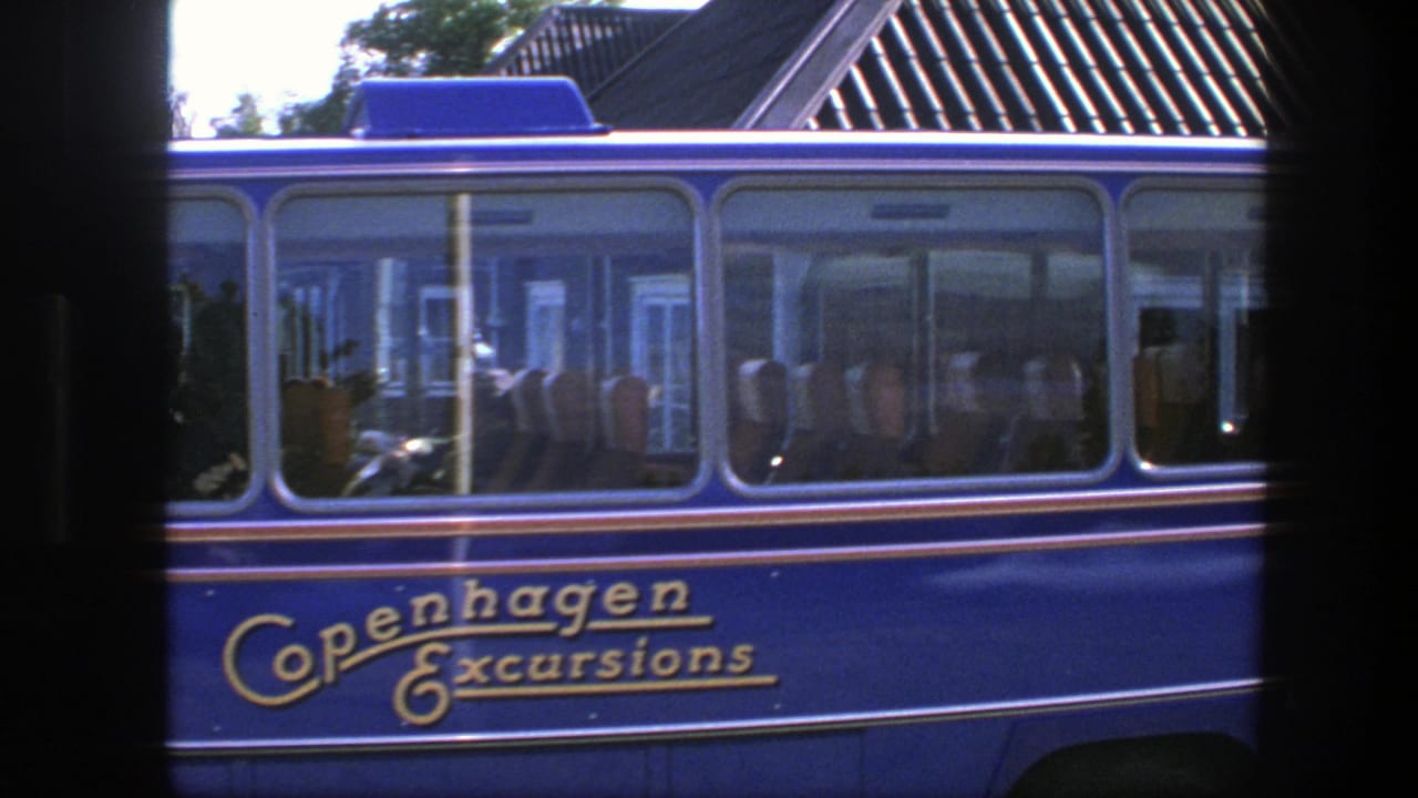 The blue Copenhagen Excursions bus fills the frame, with seated passengers and window reflections visible in the 8mm shot.