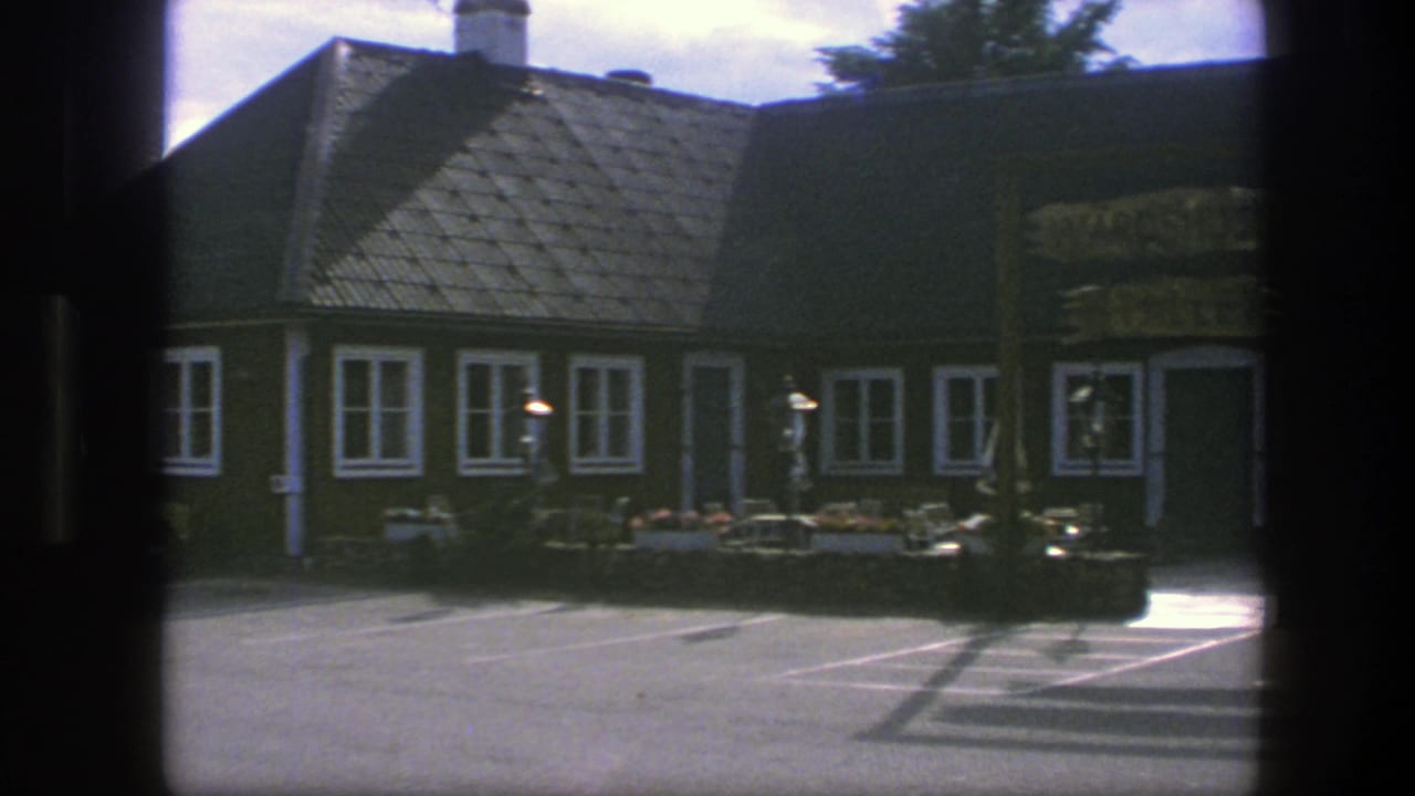 1975 Copenhagen exterior with a traditional brown building, white window trim, tiled roof, wooden signage, and flower boxes along the front.