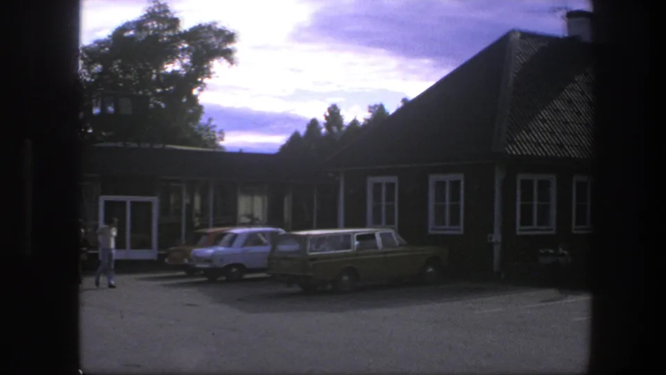 1975 Copenhagen view of three parked cars outside a brown-and-white building, with a pedestrian near the entrance.