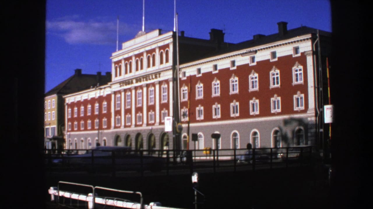 1975 Copenhagen view of a signed red hotel building, framed by dark foreground edges and street railings.