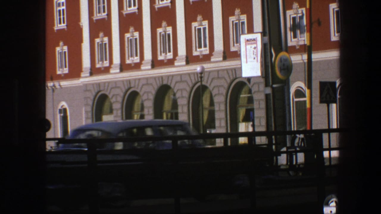 1975 Copenhagen street view of an ornate red and white hotel facade, partly obscured by dark foreground framing and a passing car.