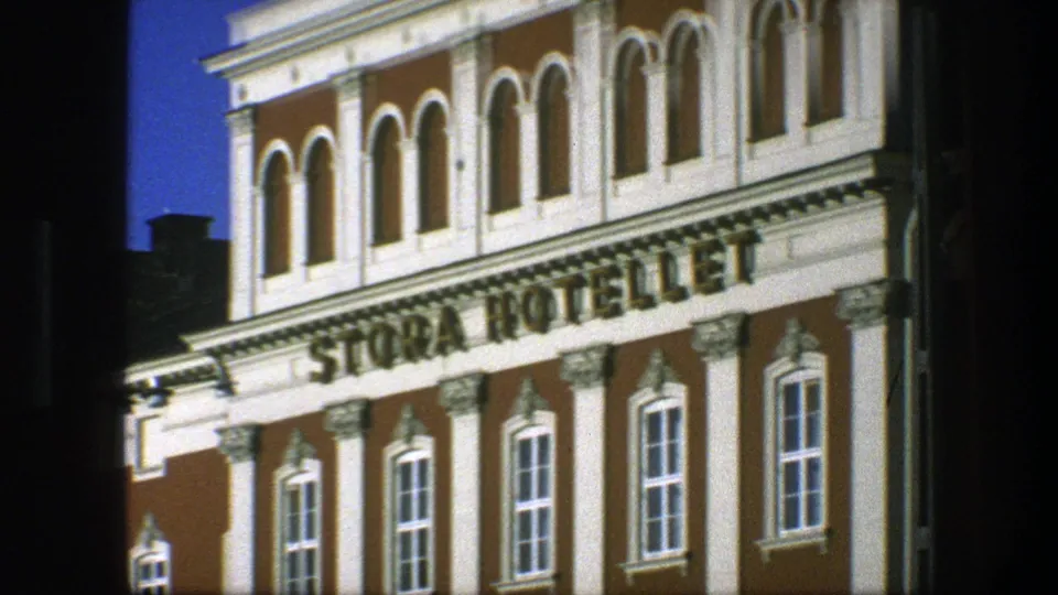 1975 Copenhagen 8mm frame showing the Stora Hotellet sign across an ornate brown-and-white facade with arched upper windows.