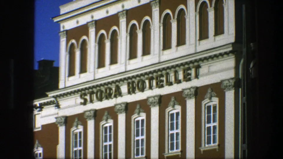 Angled 1975 Copenhagen 8mm frame of the Stora Hotellet facade, showing the large sign, white trim, and rows of tall windows.