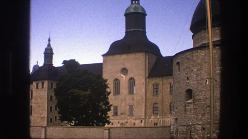 Copenhagen 1975 home-movie frame showing a historic waterfront building, domed roof, stone tower, tree, wall, and dark foreground framing.