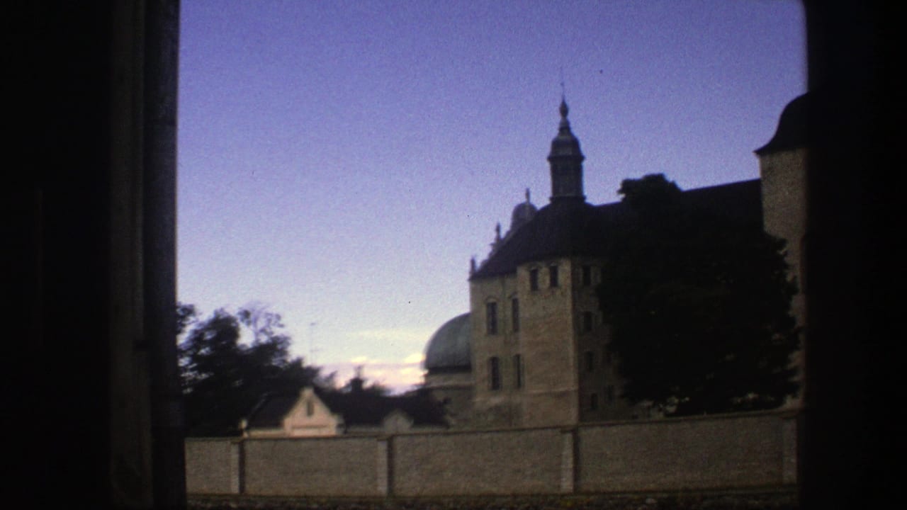 Towered historic building and dome behind a wall under a blue twilight sky.