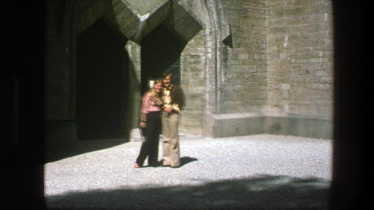 Two women stand together outside a stone building with an arched doorway.