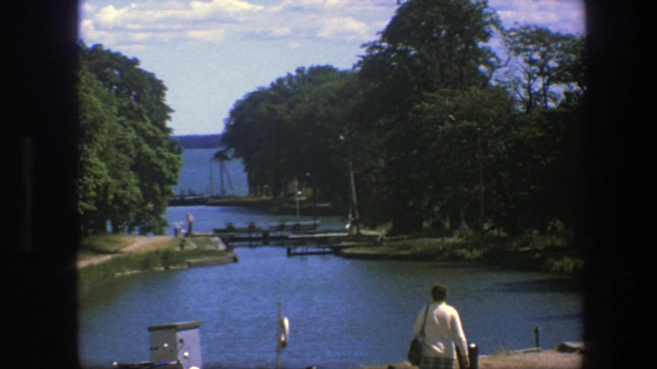 Canal view with trees, distant people, and a person entering the lower foreground.