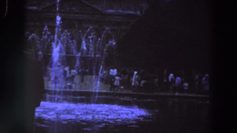 1961 Ireland home-movie view of a nighttime fountain with visitors lined along the far side.