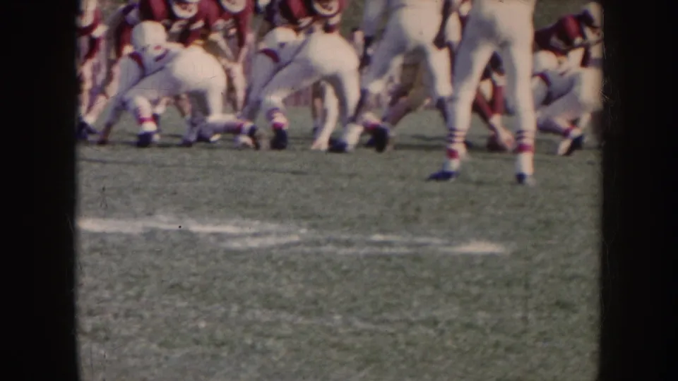 1957 Nebraska football footage shows players in white uniforms with red accents facing red-jerseyed opponents near the line of scrimmage.
