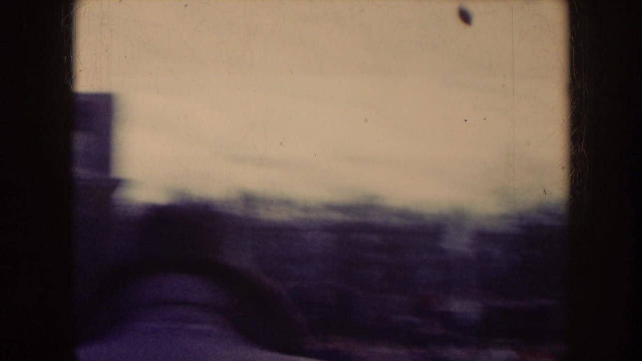 Blurred view past stadium structure or seating with warm sky and dark vertical frame edge.