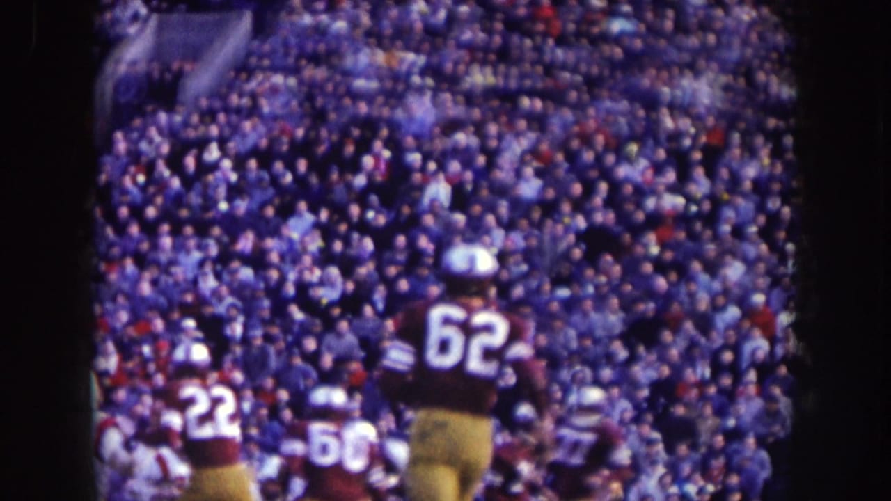 Football players in maroon and gold uniforms, including visible numbers 22 and 62, move across the field in Nebraska stadium footage.