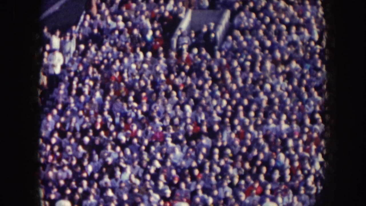 Nebraska 1957 home-movie view of densely packed football stands, with spectators filling the frame in soft 8mm color.