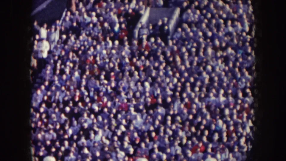 Nebraska 1957 home-movie view of densely packed football stands, with spectators filling the frame in soft 8mm color.