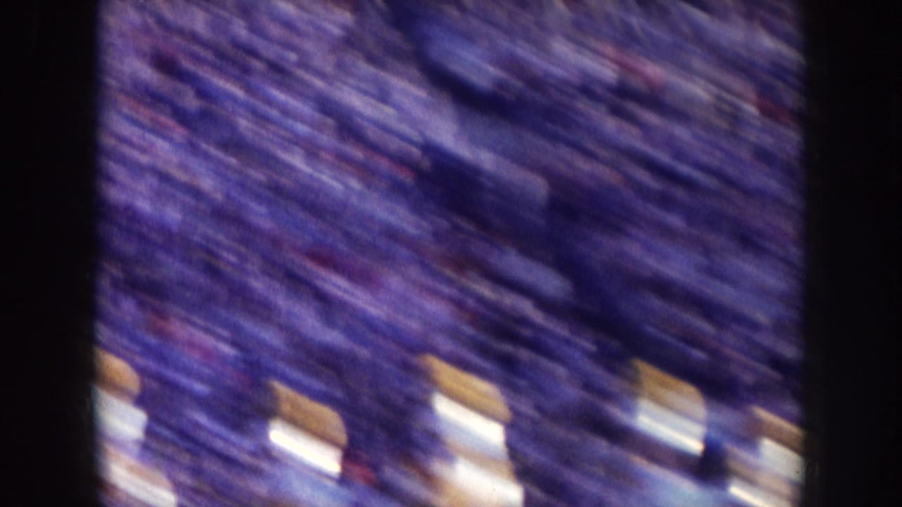 Blurred high-angle view of a packed stadium crowd with light figures near the bottom edge.