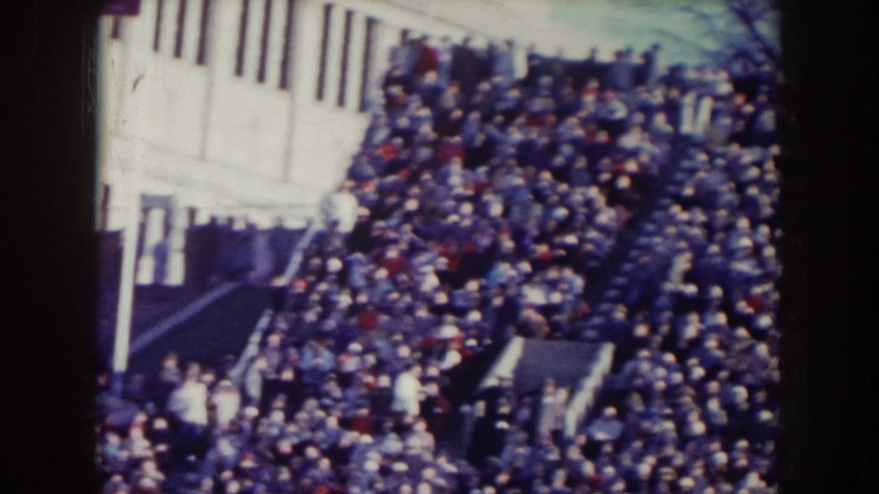 Dense outdoor crowd beside a pale building and stairway.