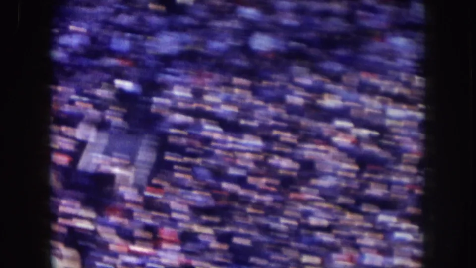 1957 Nebraska home-movie frame with a rapid pan across a large crowd, producing strong motion blur.