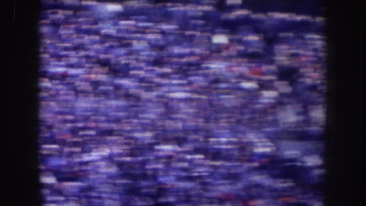 Purple-tinted 1957 Nebraska 8mm view of densely filled stadium bleachers, blurred by motion and film grain.