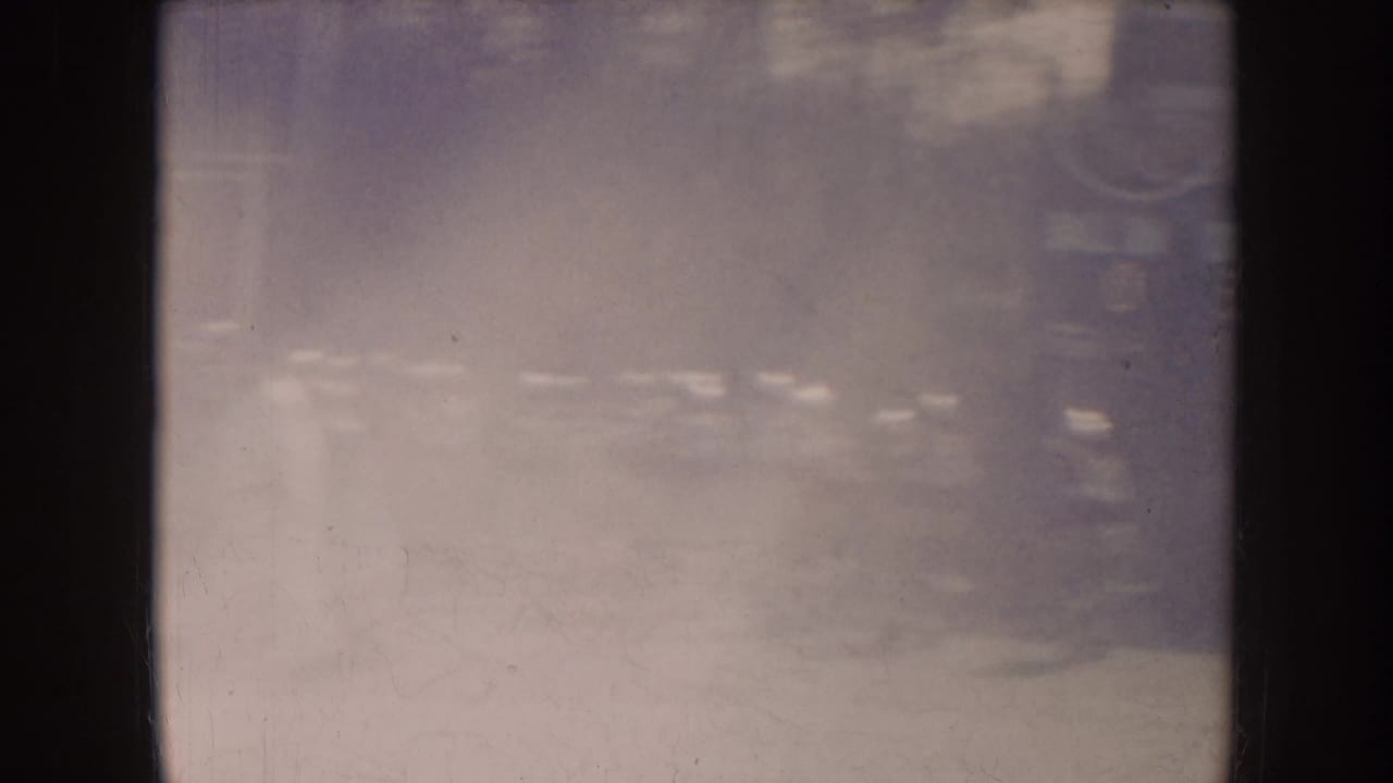 A hazy field view shows distant players or spectators near the edge of play.