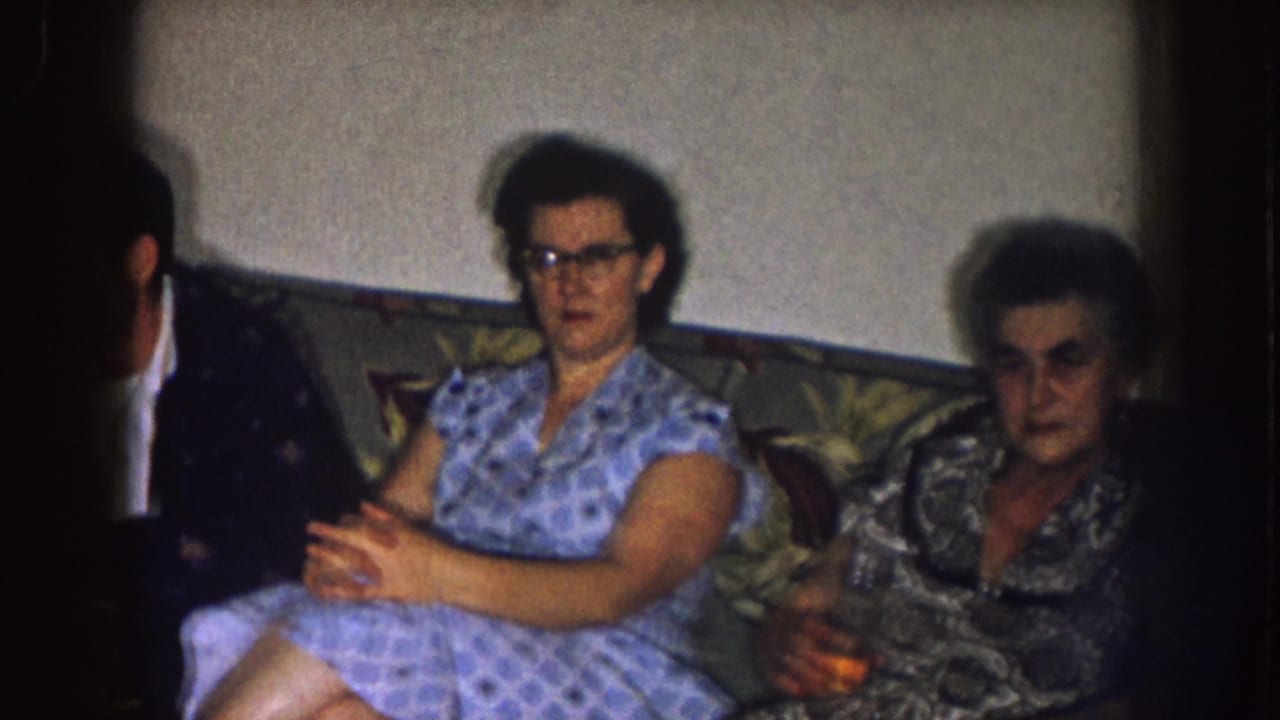 Two women sit beside a partially visible man on a couch.
