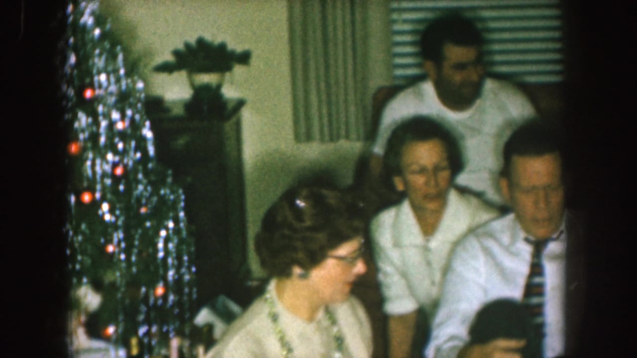 Family members seated in a living room beside a silver Christmas tree.