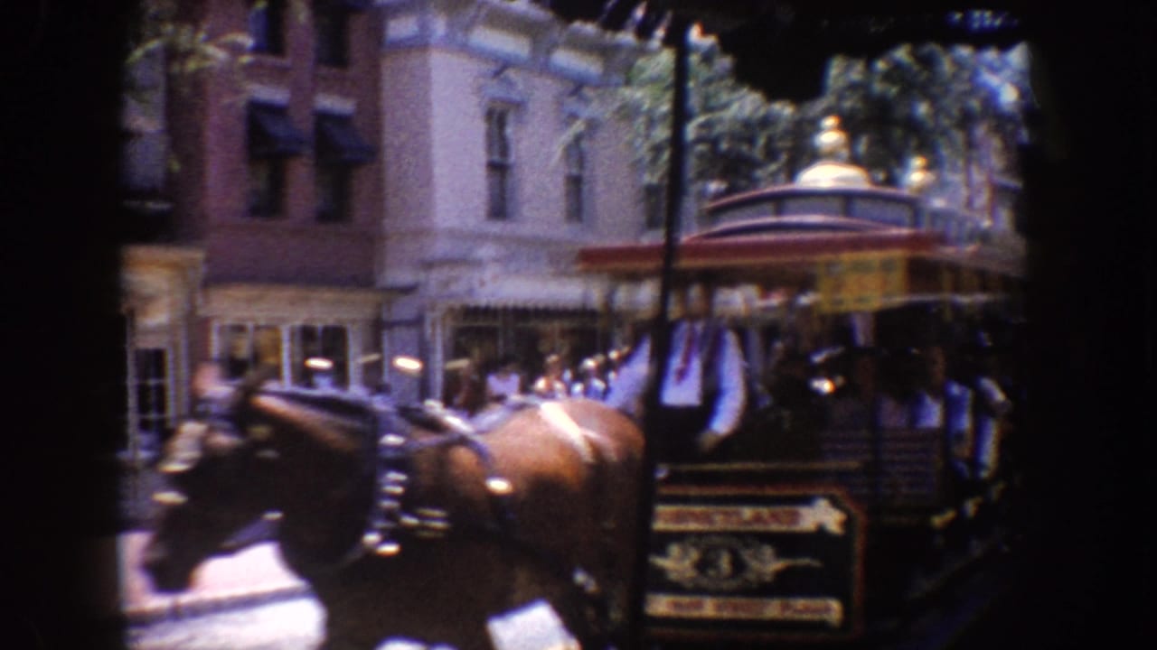 Horse-drawn trolley passing storefronts with pedestrians nearby.