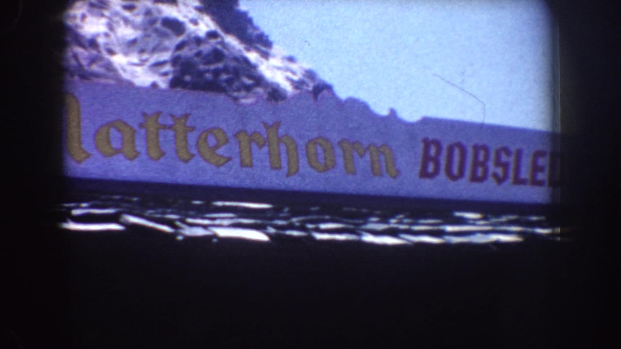 1962 Disneyland home-movie frame showing part of the Matterhorn Bobsleds sign and alpine backdrop.