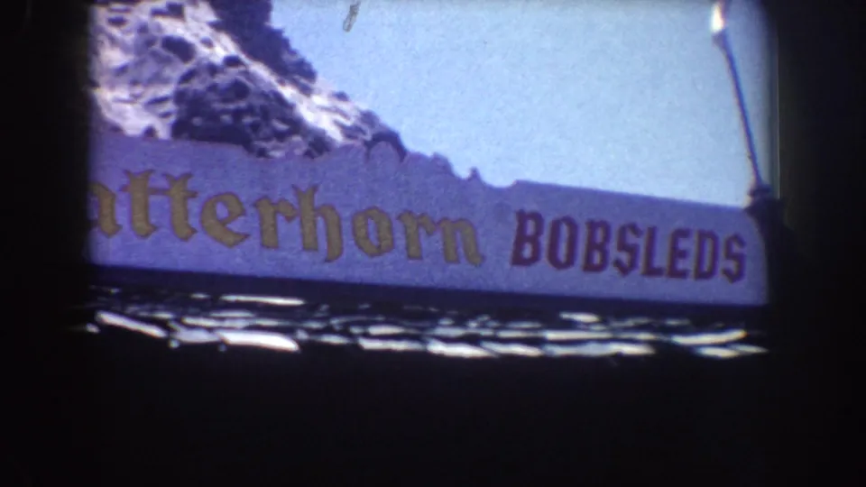 Cropped 1962 Disneyland view of the Matterhorn Bobsleds sign, with purple paneling and alpine artwork above.
