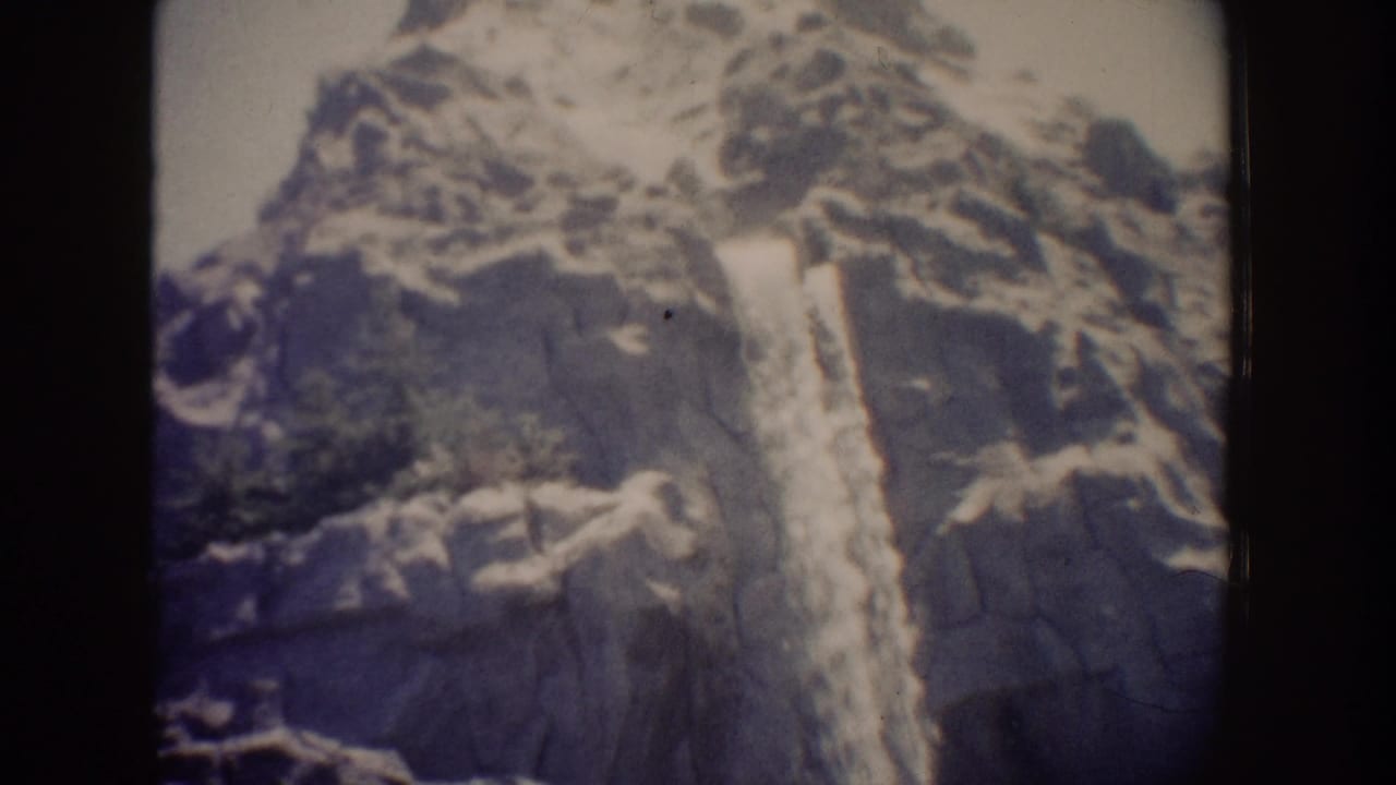 Waterfall centered against steep rocks with dark frame borders visible.