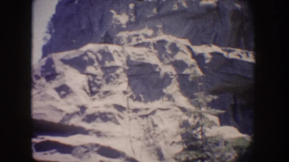 1962 Disneyland home-movie frame showing a soft, grainy rocky landscape seen through or on a rectangular lit surface inside a dark ride.
