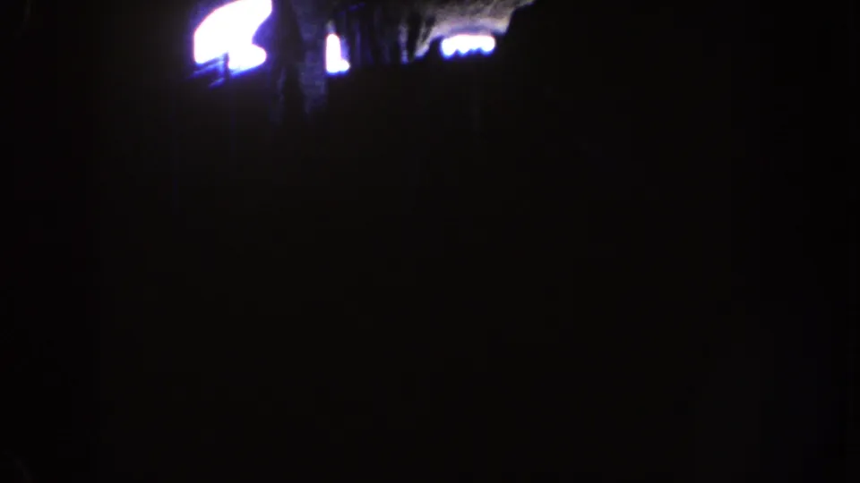 Dark 1962 Disneyland ride-interior frame with a small bright flare or opening near the top and little visible detail elsewhere.