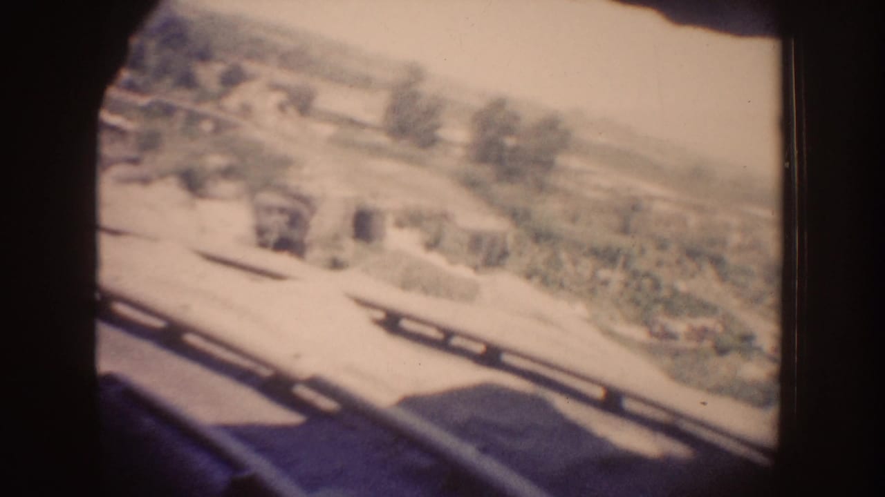 Sunlit exterior seen through a train window or tunnel opening.
