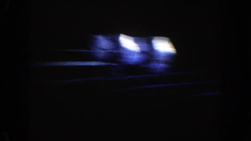 1962 Disneyland ride footage begins in near darkness, with blurred blue-white lights and faint track-like lines across the frame.