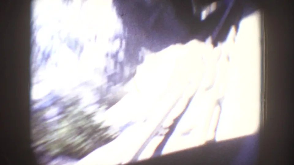 Motion-blurred Disneyland ride view with a bright tunnel-like opening, vertical structure, and streaked outdoor or lit background detail.